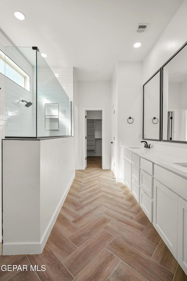 full bathroom featuring baseboards, visible vents, recessed lighting, a sink, and a walk in shower