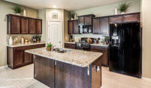 kitchen featuring stove, dark brown cabinets, a kitchen island with sink, and black refrigerator with ice dispenser