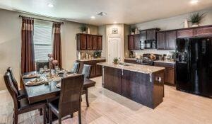 kitchen with dark brown cabinetry, black fridge with ice dispenser, and a center island with sink