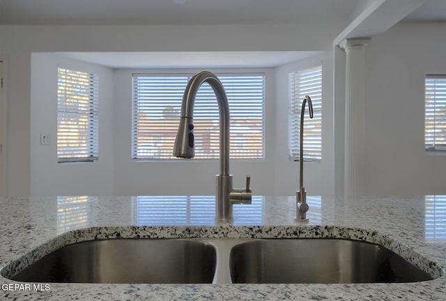 details with light stone countertops, decorative columns, and a sink