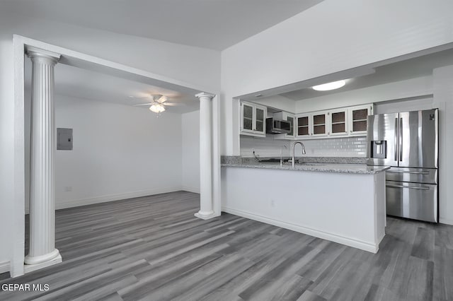 kitchen featuring dark wood-type flooring, glass insert cabinets, decorative backsplash, stainless steel appliances, and ornate columns