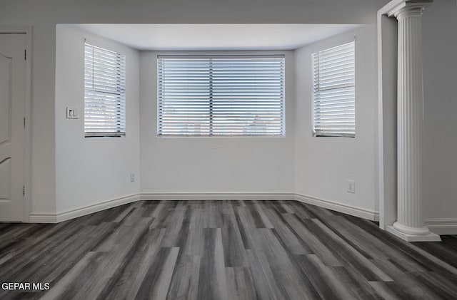 spare room featuring decorative columns, baseboards, and wood finished floors