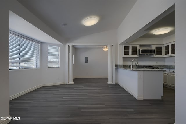 kitchen featuring tasteful backsplash, stainless steel microwave, glass insert cabinets, vaulted ceiling, and a peninsula