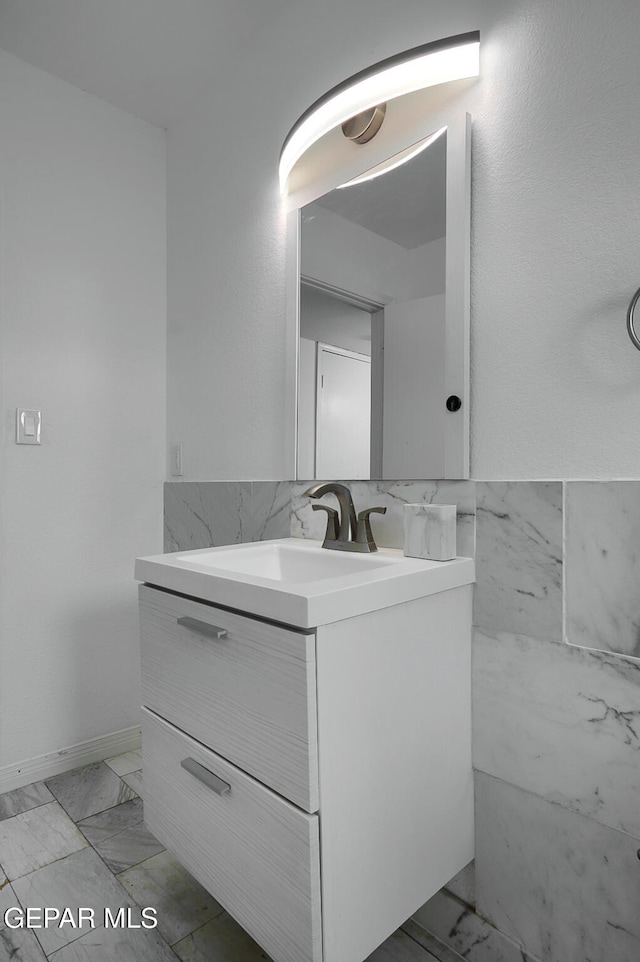 bathroom featuring marble finish floor, vanity, and tile walls