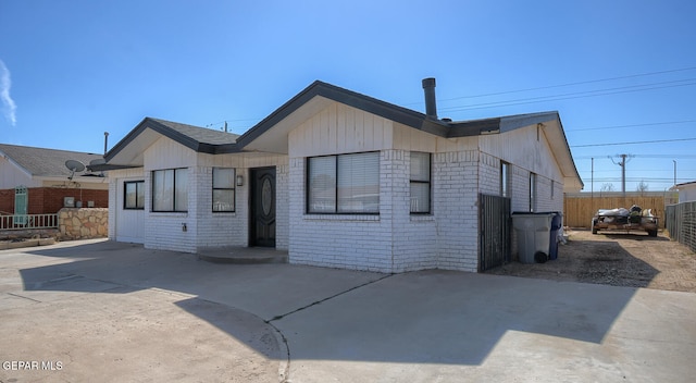 rear view of house with a patio, brick siding, and fence