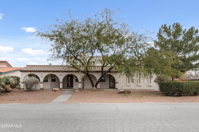 mediterranean / spanish house featuring a tiled roof, covered porch, and stucco siding