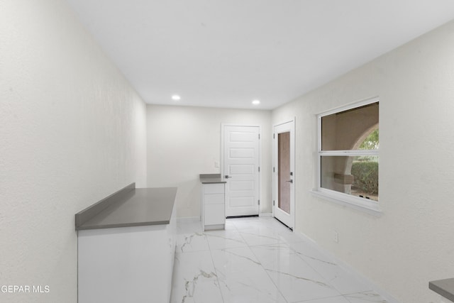 interior space featuring dark countertops, baseboards, recessed lighting, marble finish floor, and white cabinetry