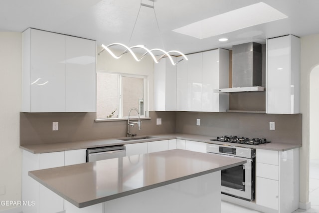 kitchen featuring a sink, stainless steel appliances, wall chimney exhaust hood, and modern cabinets