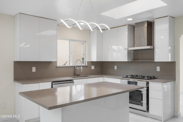 kitchen with a sink, oven, wall chimney range hood, gas stovetop, and modern cabinets