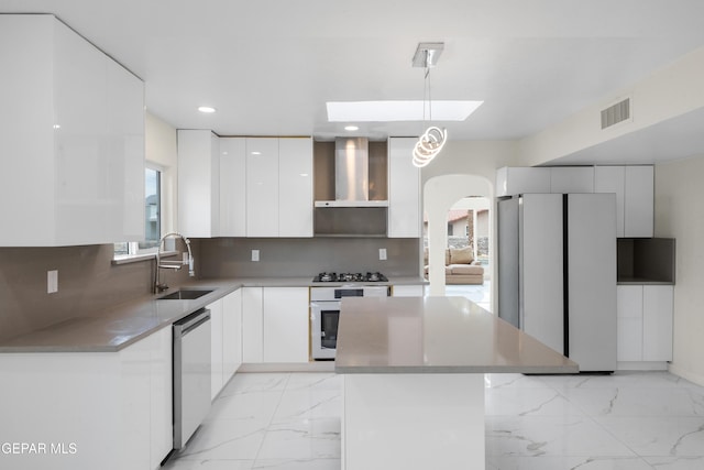 kitchen with marble finish floor, modern cabinets, a sink, stainless steel appliances, and wall chimney range hood