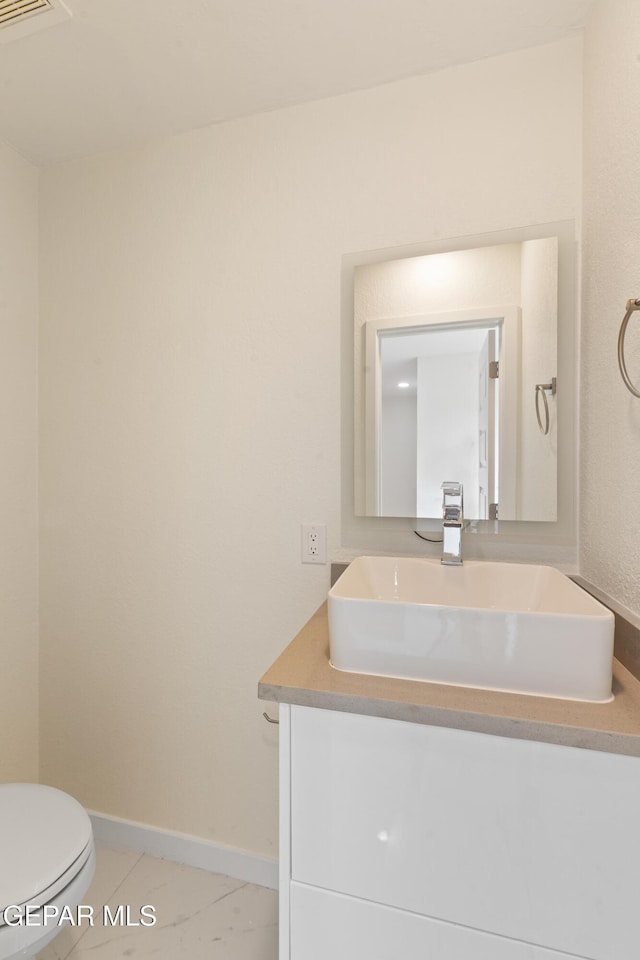 half bath with vanity, visible vents, baseboards, tile patterned floors, and toilet