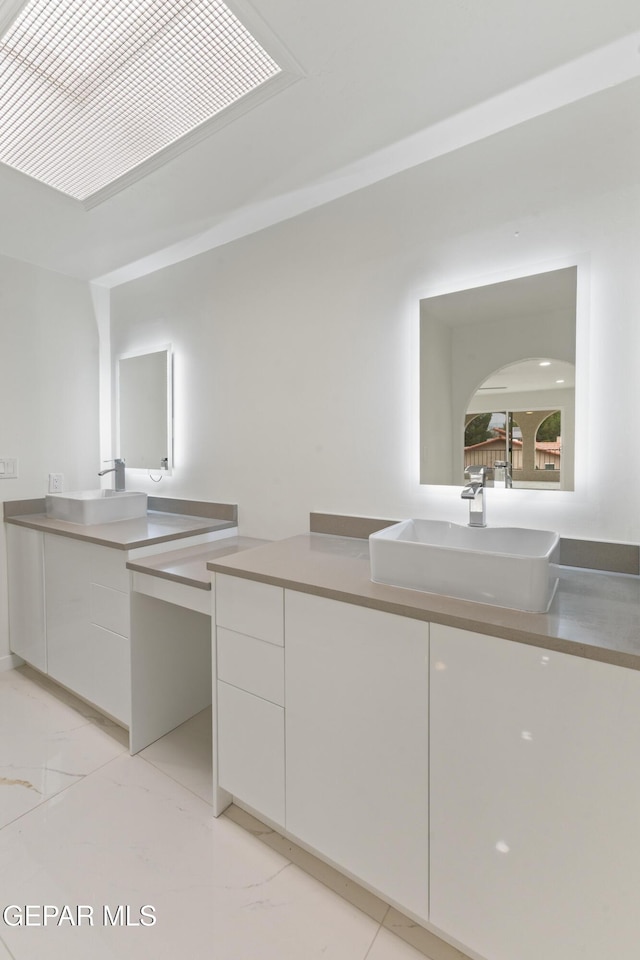 bathroom featuring marble finish floor, two vanities, and a sink