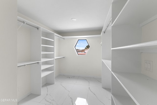 walk in closet featuring marble finish floor