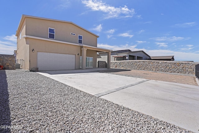 view of front of home featuring stucco siding, driveway, central AC, fence, and an attached garage