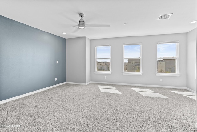 empty room featuring visible vents, ceiling fan, carpet flooring, and baseboards