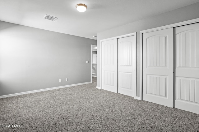 unfurnished bedroom featuring visible vents, multiple closets, baseboards, and carpet flooring