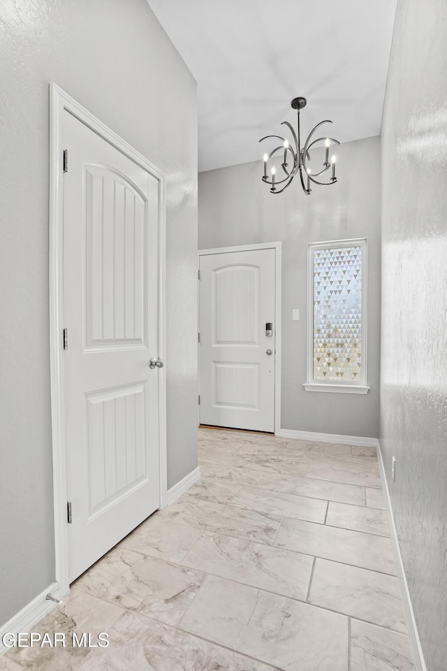 entrance foyer featuring a notable chandelier, baseboards, and marble finish floor