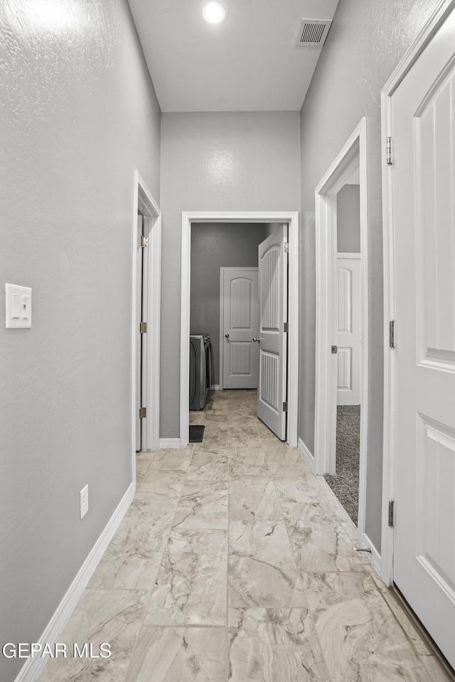 hallway featuring visible vents, baseboards, marble finish floor, and washing machine and dryer