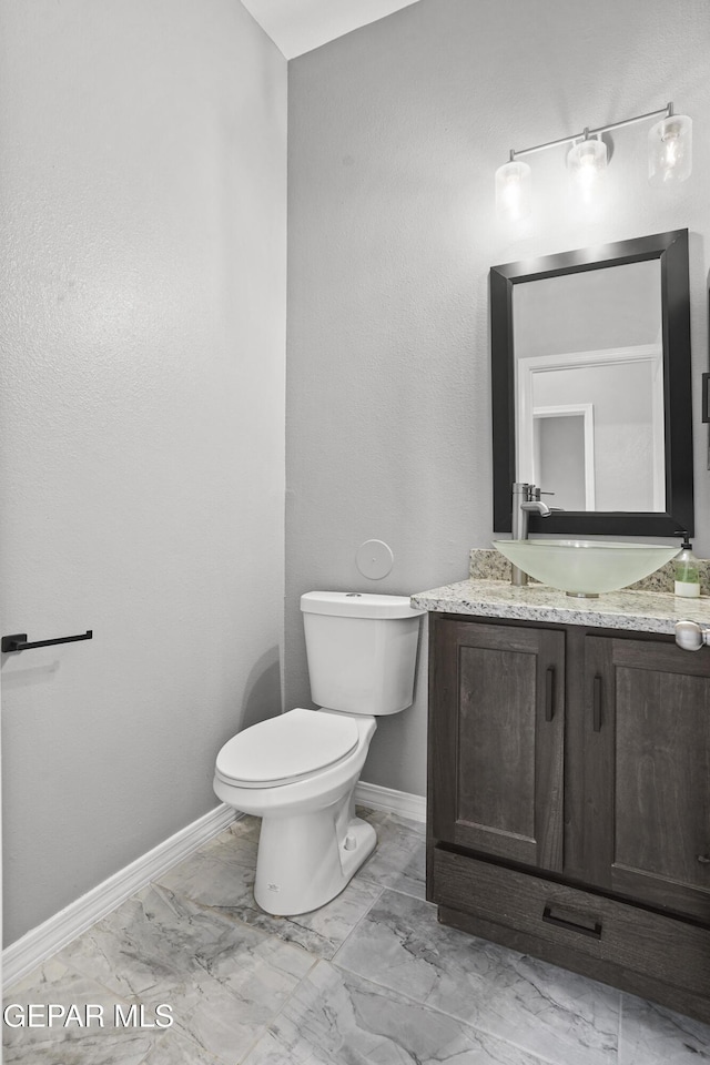 bathroom featuring baseboards, toilet, marble finish floor, and vanity