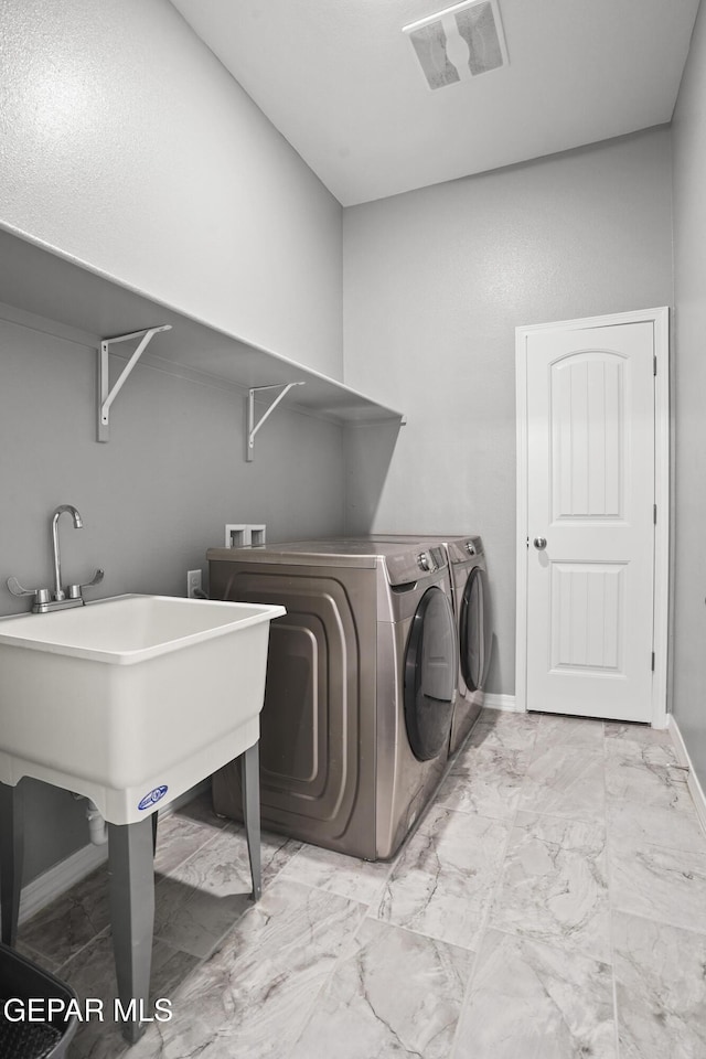 laundry area with independent washer and dryer, laundry area, baseboards, and marble finish floor