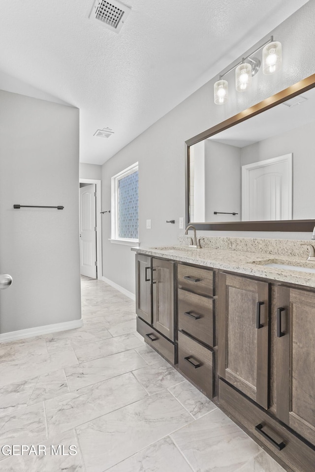 bathroom with double vanity, visible vents, and marble finish floor