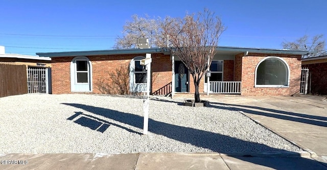 ranch-style home featuring brick siding and covered porch