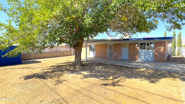 view of front of home with a patio area, brick siding, and fence