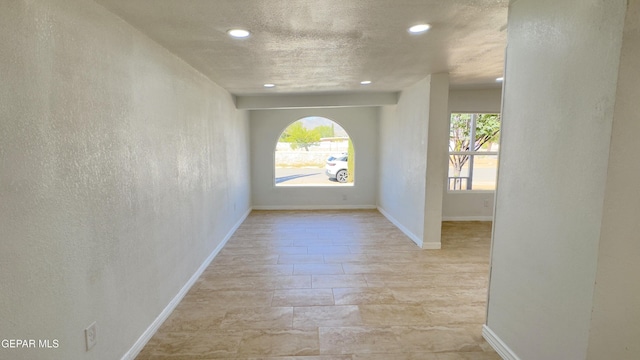 unfurnished room with a wealth of natural light, baseboards, a textured ceiling, and recessed lighting