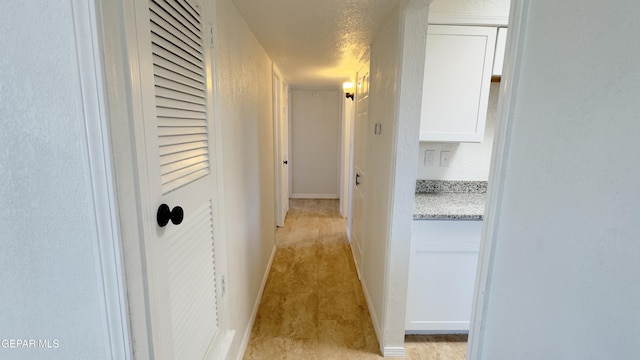 hallway with baseboards and a textured ceiling