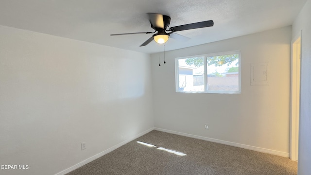 carpeted empty room featuring a ceiling fan and baseboards