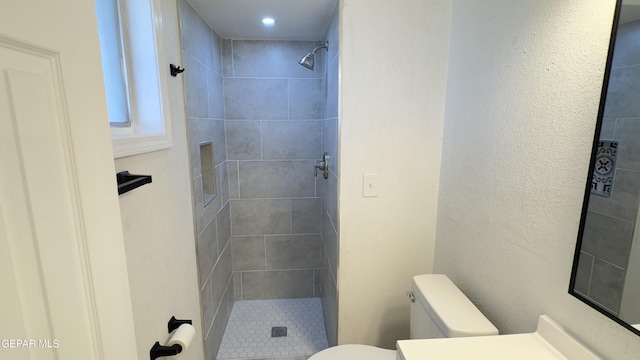 bathroom with vanity, toilet, and tiled shower