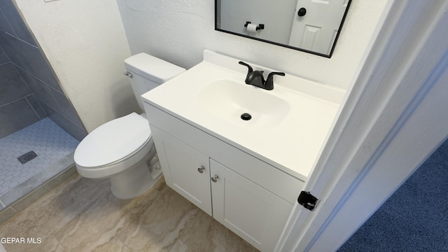 full bath with tiled shower, toilet, vanity, and a textured wall