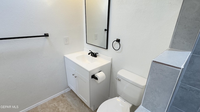 bathroom featuring toilet, vanity, and baseboards