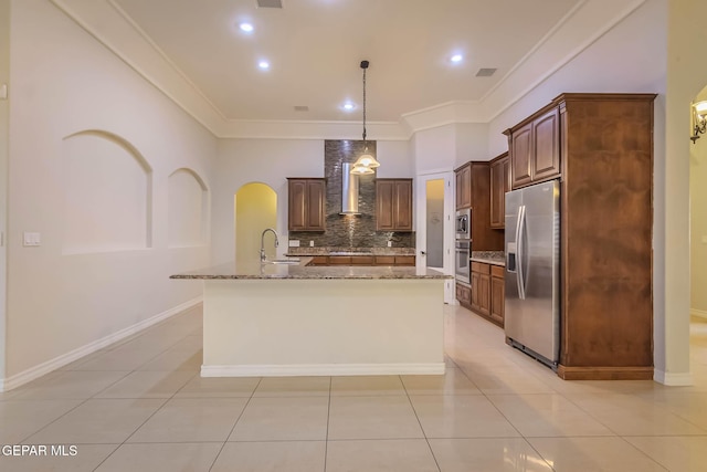 kitchen with arched walkways, stainless steel appliances, wall chimney range hood, and ornamental molding