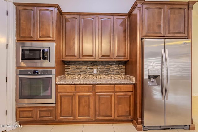 kitchen with light tile patterned floors, stainless steel appliances, light stone countertops, and decorative backsplash