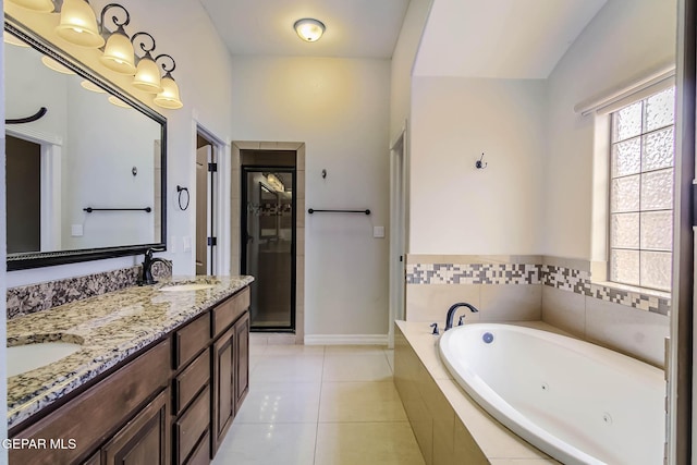 bathroom with tile patterned floors, a tub with jets, double vanity, and a sink