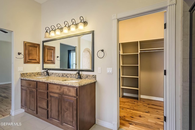 bathroom with double vanity, wood finished floors, baseboards, and a sink