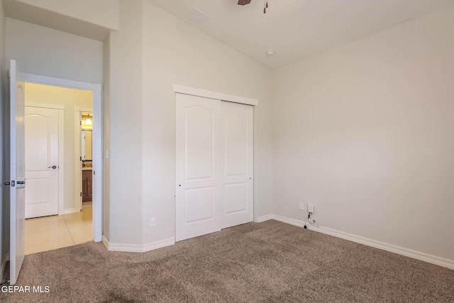 unfurnished bedroom with a closet, baseboards, carpet flooring, and vaulted ceiling