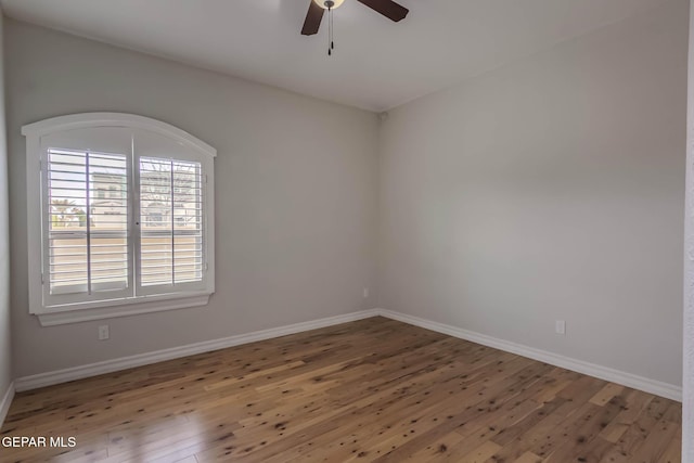 spare room with hardwood / wood-style flooring, a ceiling fan, and baseboards