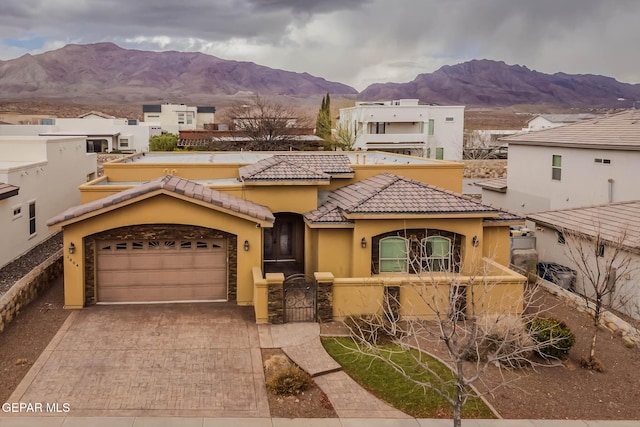 view of front of home with stucco siding, a tile roof, decorative driveway, a mountain view, and an attached garage