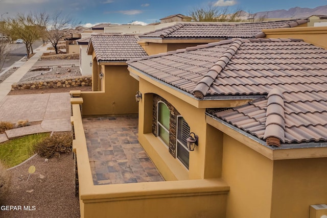 view of side of home with a tile roof, a patio area, and stucco siding