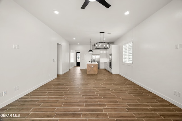 unfurnished living room with wood finish floors, recessed lighting, baseboards, and a ceiling fan