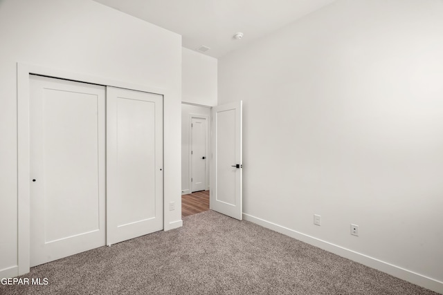 unfurnished bedroom with a closet, carpet flooring, and baseboards