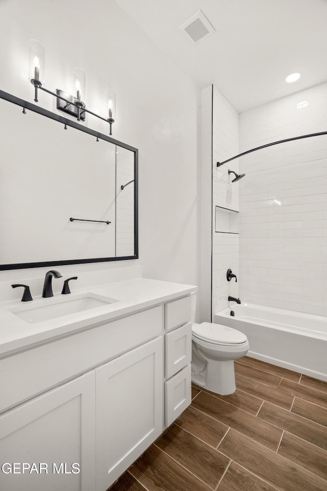 bathroom featuring visible vents, toilet, wood tiled floor, washtub / shower combination, and vanity