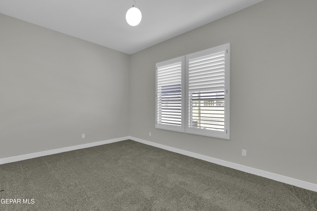 unfurnished room featuring baseboards and dark carpet