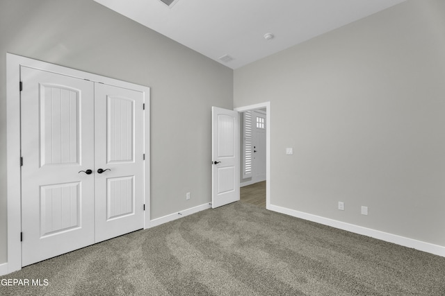 unfurnished bedroom featuring baseboards, carpet floors, a closet, and visible vents