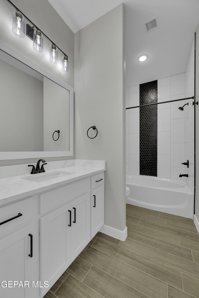 full bathroom with visible vents, baseboards, wood tiled floor, toilet, and vanity