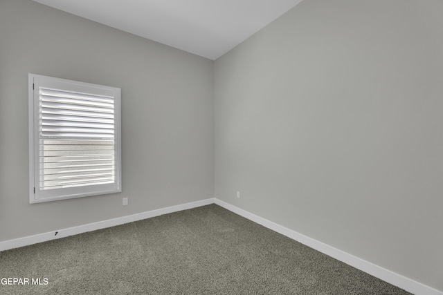 empty room with dark colored carpet and baseboards