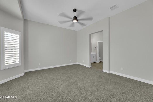 empty room featuring visible vents, baseboards, a ceiling fan, and dark colored carpet