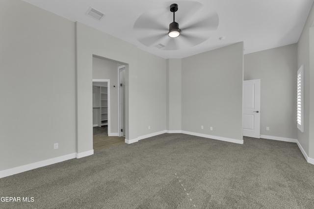 empty room featuring baseboards, visible vents, dark colored carpet, and ceiling fan